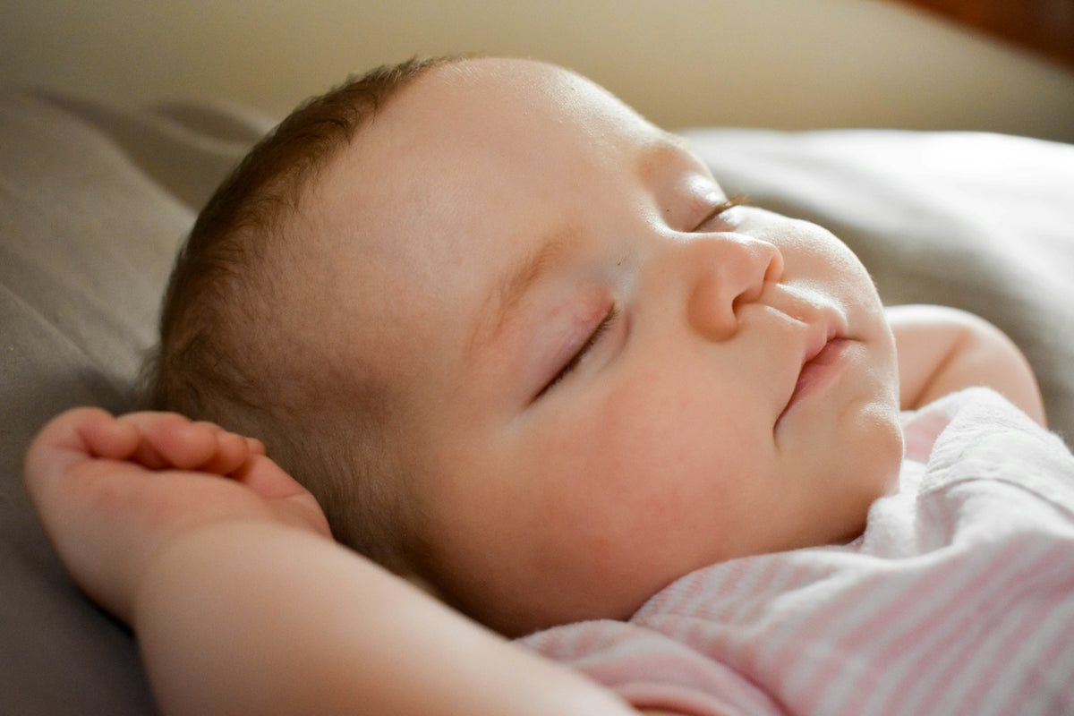 A baby sleeping peacefully on a soft cushion