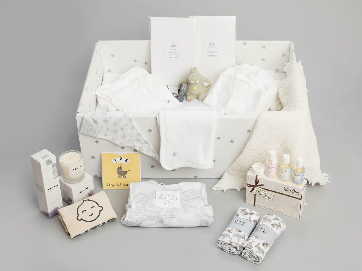 A new baby gift hamper with its contents laid out, including clothes and keepsakes