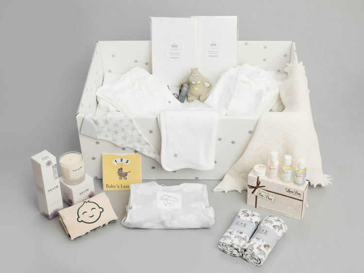 A new baby gift hamper with its contents laid out, including clothes and keepsakes